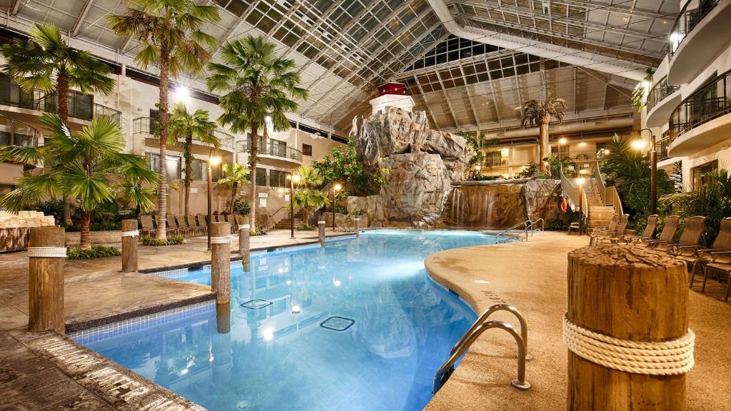 a large swimming pool in a hotel with a waterfall at Best Western Plus Lamplighter Inn & Conference Centre in London