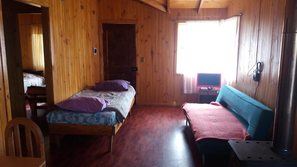 a small bedroom with a bed and a window at Cabanas Neptuno in Quellón