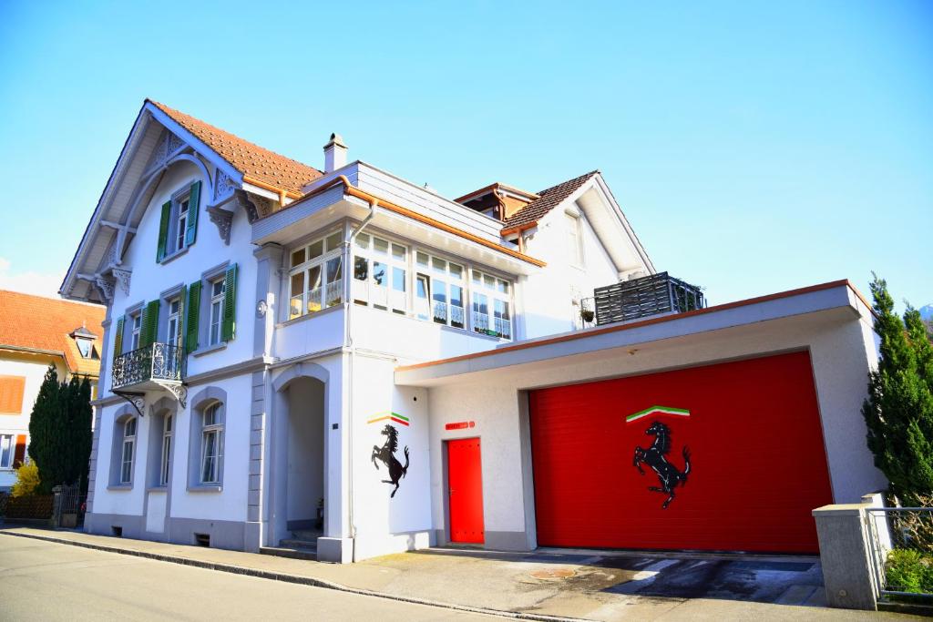 a white house with red garage doors with a painting on it at Ferrari Apartment in Interlaken