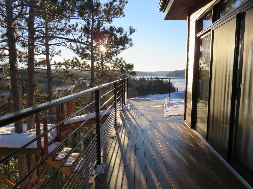 a balcony of a house with a view of the water at Gîte du Haut des Arbres in Saguenay