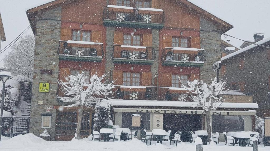 a large brick building with snow in front of it at Hotel Esquirol in Llivia