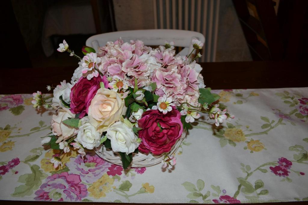 Trulli Aia Piccola في ألبيروبيلو: باقة من الزهور الزهرية والبيضاء الجالسة على الطاولة