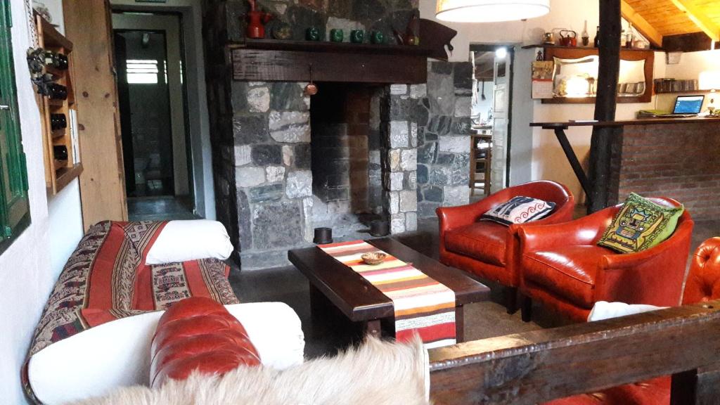 una sala de estar con sofás y una chimenea de piedra. en Estancia San Miguel en Villa Yacanto