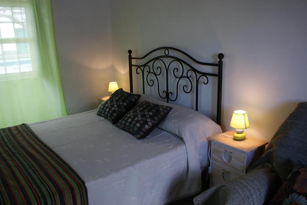 a bedroom with a bed with two lamps and a couch at Cantinho do mar in Urzelina