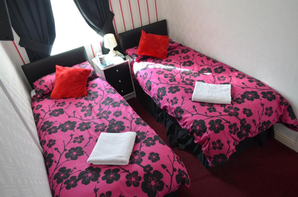 ブラックプールにあるFranklin Hotelのピンクのシーツと赤い枕が備わる客室内のベッド2台