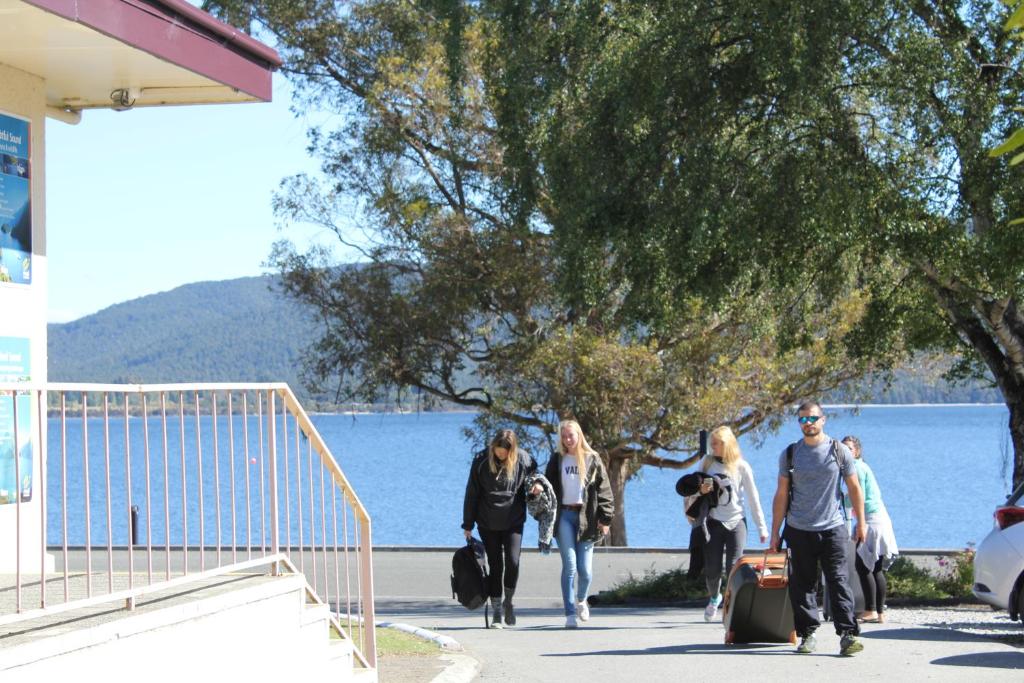 people walking down a sidewalk near a body of water at Te Anau Lakefront Backpackers in Te Anau