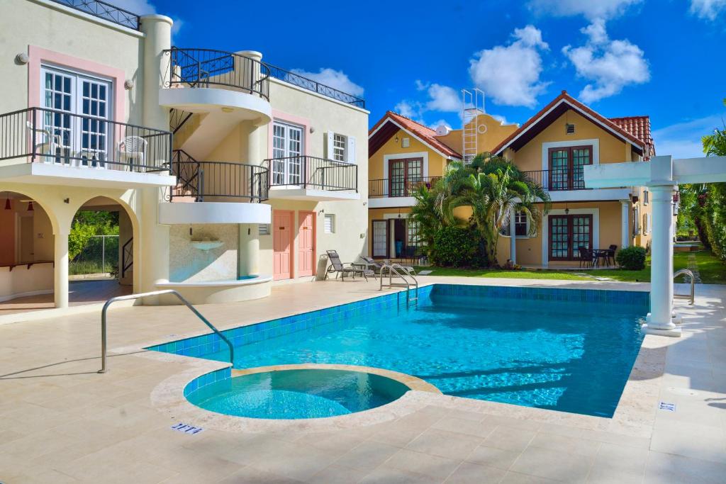 a villa with a swimming pool in front of a house at 10 Springcourt Barbados in Bridgetown