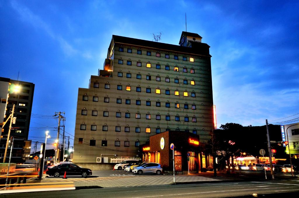 un edificio alto con coches estacionados frente a él en Grand Park Hotel Panex Kimitsu, en Kimitsu