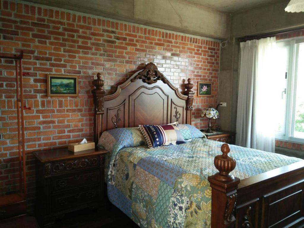 東勢區的住宿－樹之間民宿 樟間 櫸間，一间卧室设有一张床和砖墙