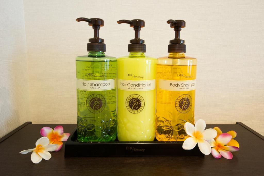 three bottles of soap and flowers on a shelf at Grand Park Hotel Panex Tokyo in Tokyo
