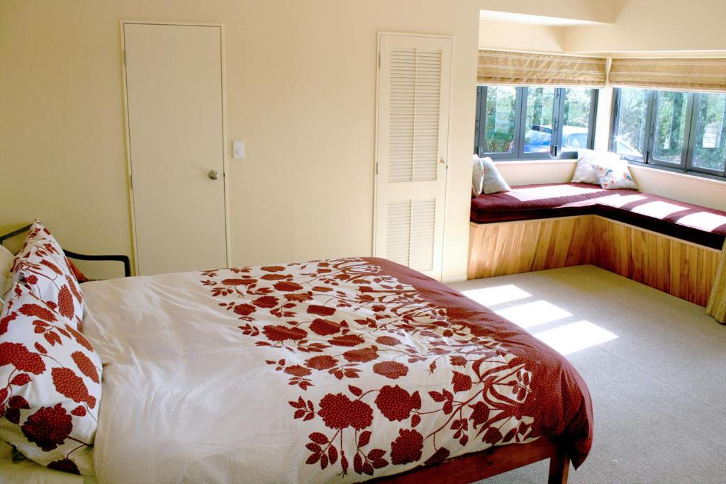 a bedroom with a bed with a red and white blanket at Strathaven Bed and Breakfast in Waipu