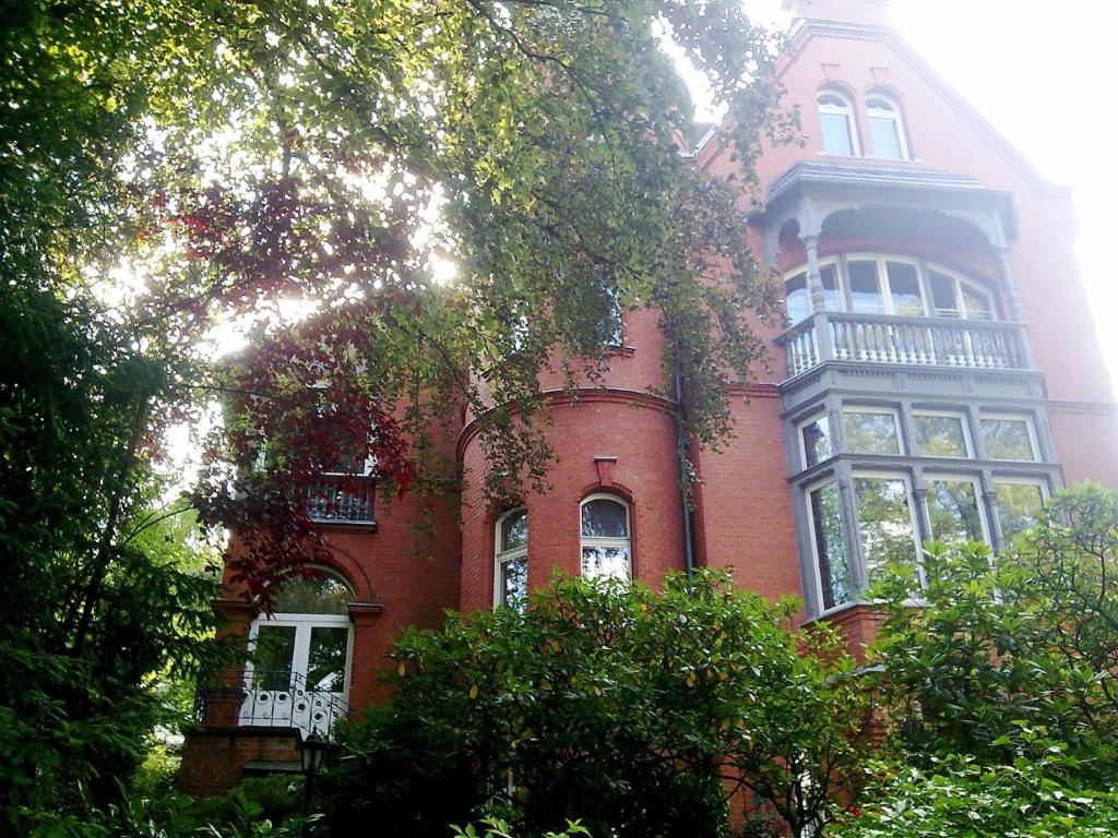 un grand bâtiment en briques rouges avec des arbres devant lui dans l'établissement Business Apartment Briller Viertel, à Wuppertal