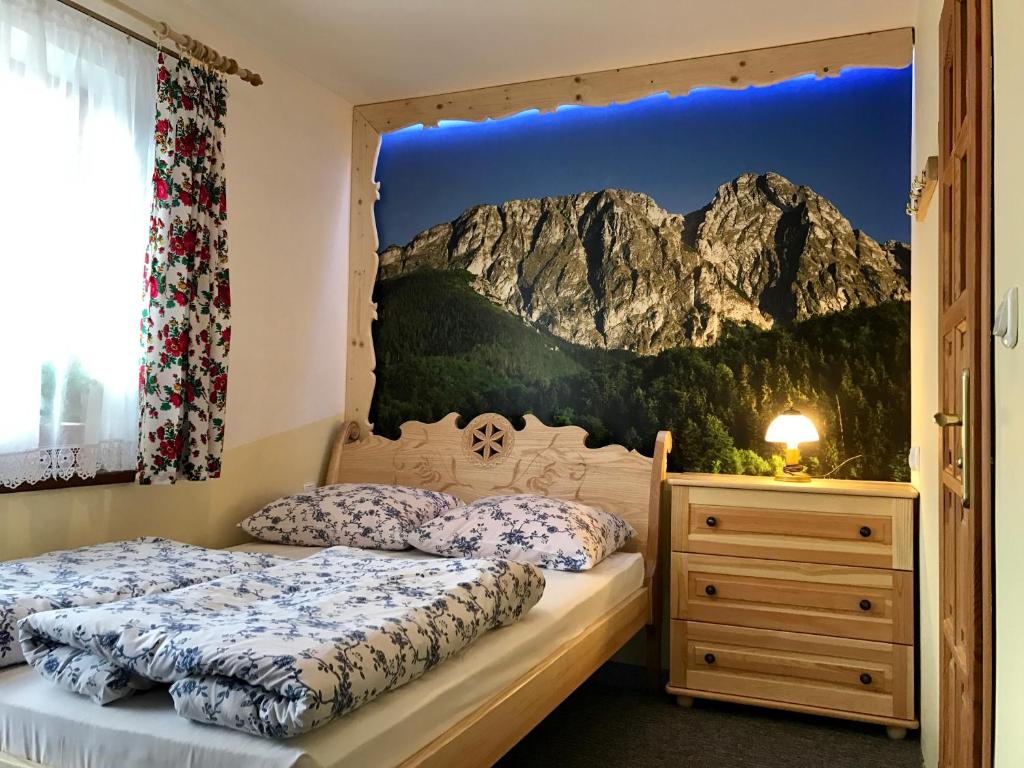 two beds in a bedroom with a mountain mural on the wall at Chatka U Hazy - Regionalne Pokoje Zakopane in Zakopane