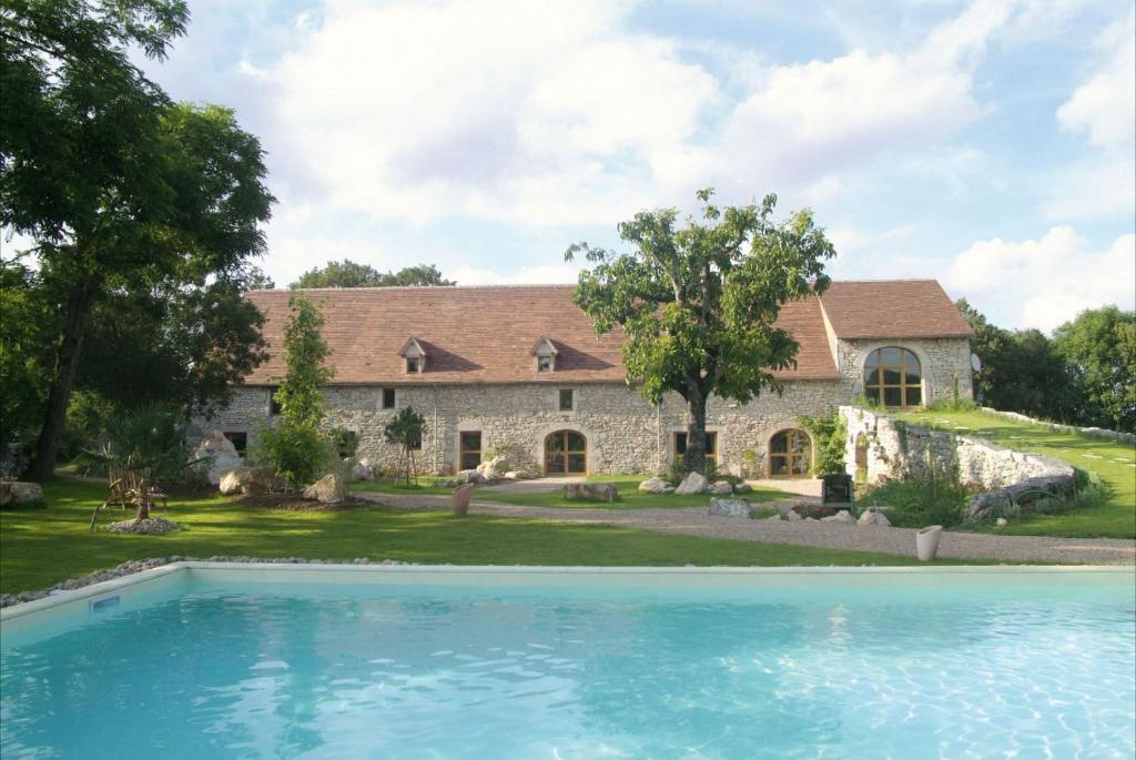 a house with a swimming pool in front of it at Chambres et Jardin de Pierres in Espédaillac