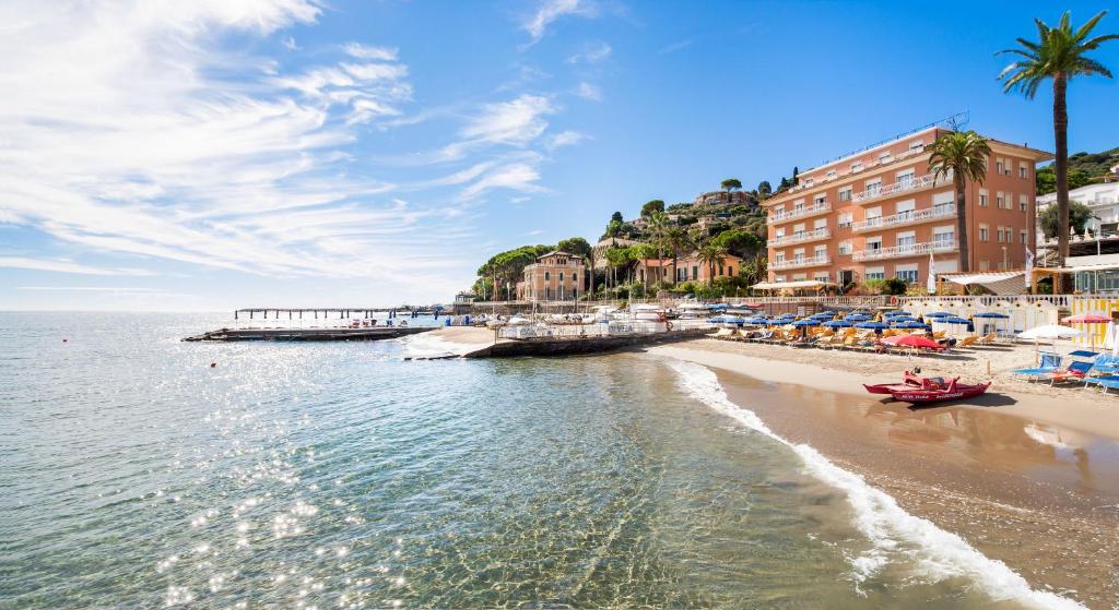 a beach with a pier and buildings and the ocean at Hotel Golfo e Palme in Diano Marina