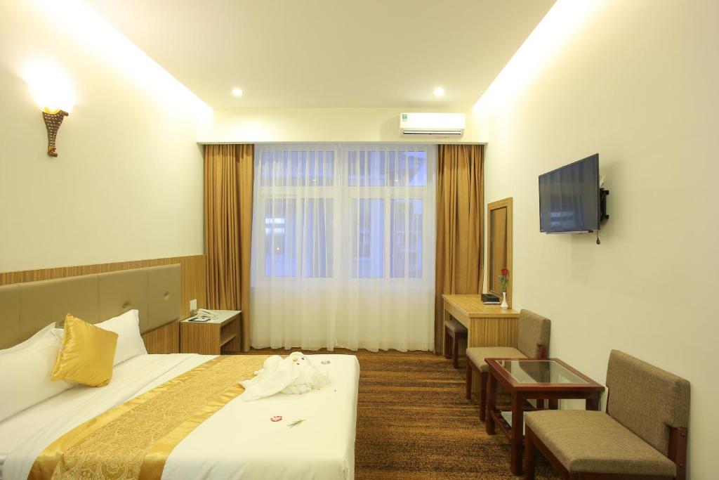 a hotel room with a bed and a desk and a television at Red Palace Hotel in Da Nang