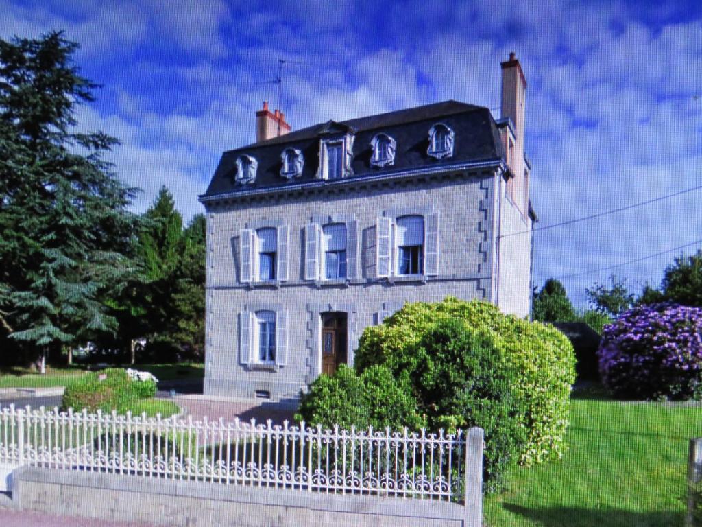 una casa vieja con una valla blanca delante de ella en La Datiniere en Parigny