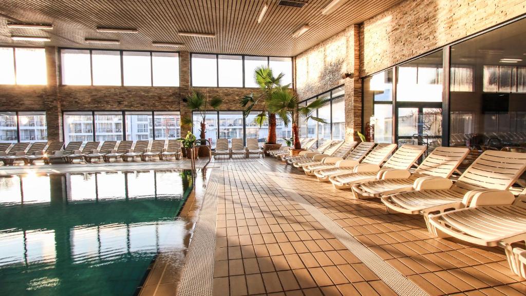 a pool with white chairs in a large building at Hotel Matija Gubec in Stubicke Toplice