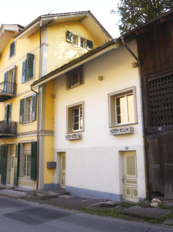 a yellow and white building with a gate and a street at The River Holiday Apartment in Interlaken