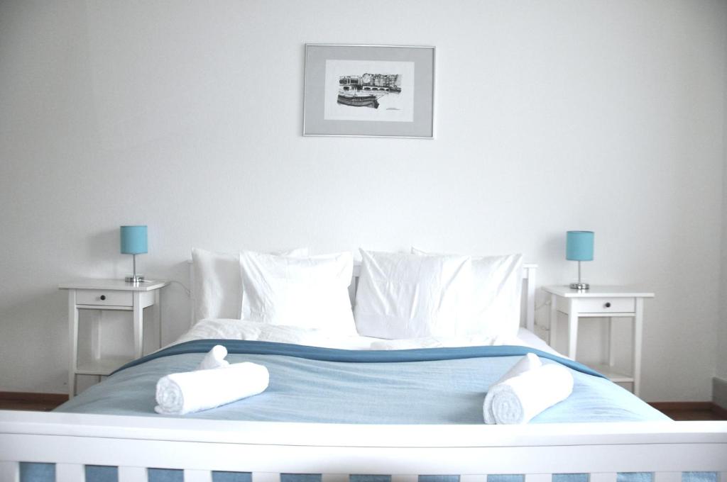 Cozy Apartment Ulmenstrasse في لوتزيرن: سرير أبيض مع سريرين بجانب سرير ذو أغطية زرقاء