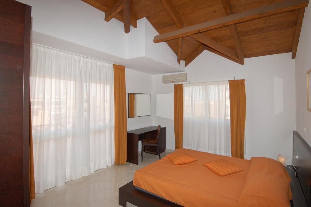 1 dormitorio con cama de color naranja y escritorio en Aparthotel Ponta Preta, en Santa Maria