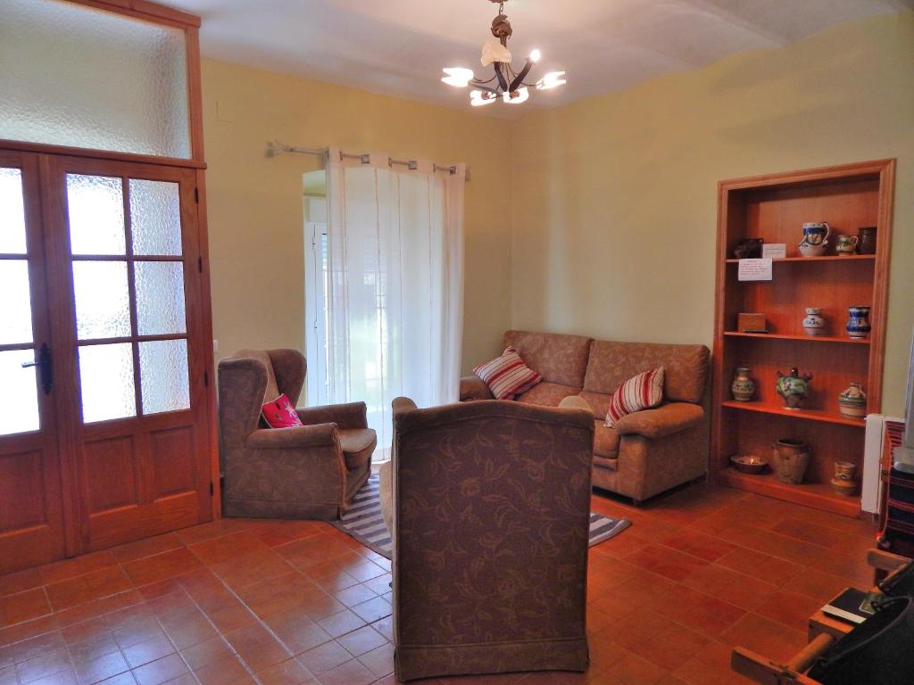 Casa Rural La Perra Gorda في Zorita: غرفة معيشة مع كرسيين وأريكة
