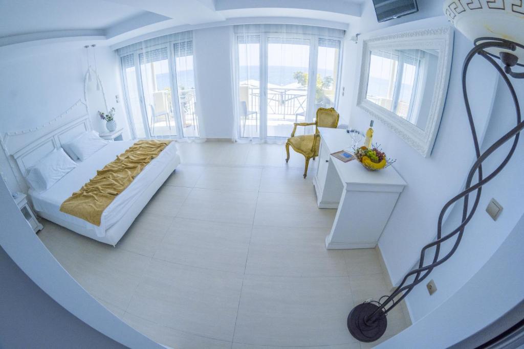 a white room with a bed and a table at Hydrele Beach Hotel & Village in Potokáki