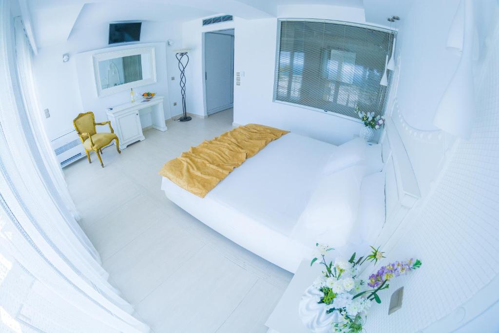 a white bedroom with a bed and a desk at Hydrele Beach Hotel & Village in Potokáki