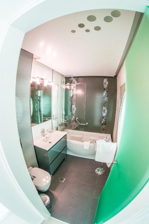 a bathroom with a tub and a toilet and a sink at Hydrele Beach Hotel & Village in Potokáki