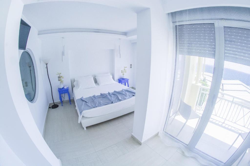 a white bedroom with a bed and a window at Hydrele Beach Hotel & Village in Potokáki