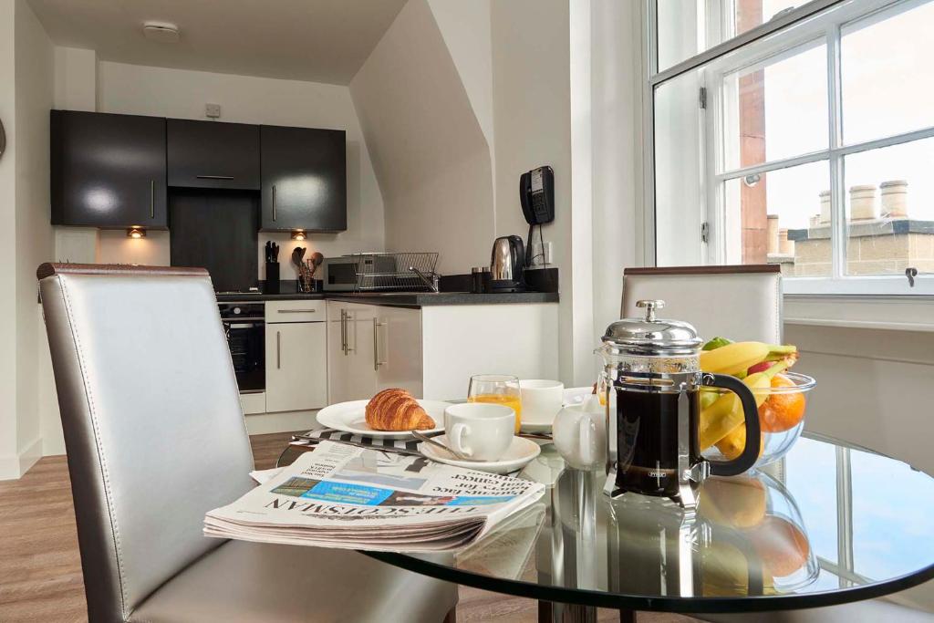 uma cozinha com uma mesa de vidro e comodidades para preparar café em Braid Apartments by Mansley em Edimburgo