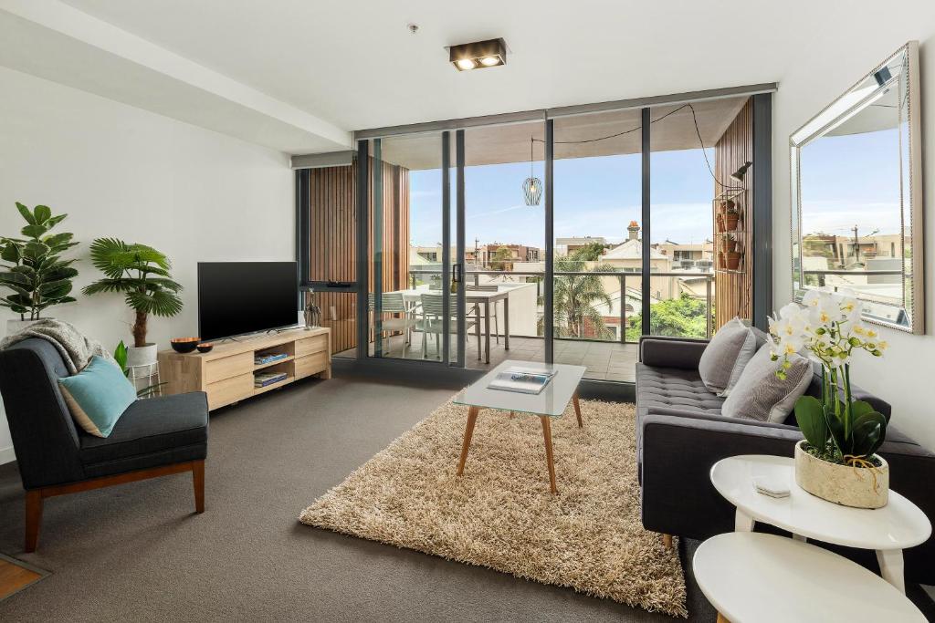 Beach Apartment Port Melbourne في ملبورن: غرفة معيشة مع أريكة وتلفزيون