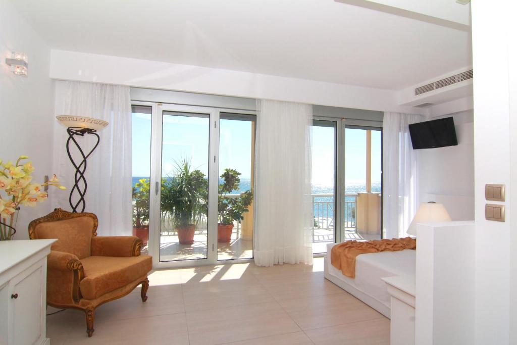 a white bedroom with a bed and a chair at Hydrele Beach Hotel & Village in Potokáki