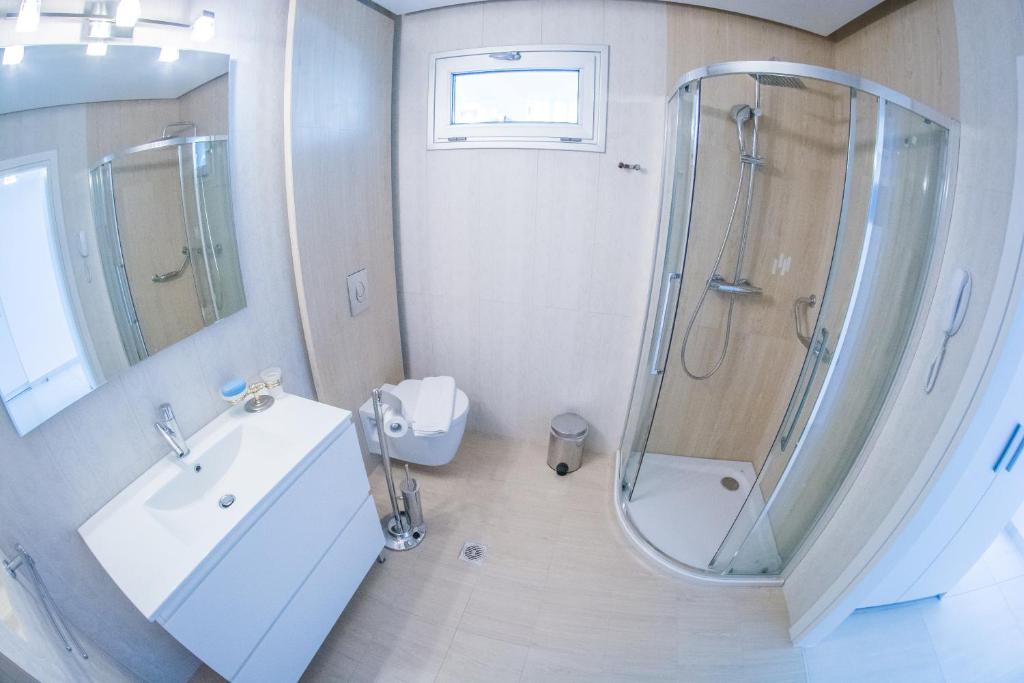a white bathroom with a shower and a sink at Hydrele Beach Hotel & Village in Potokáki
