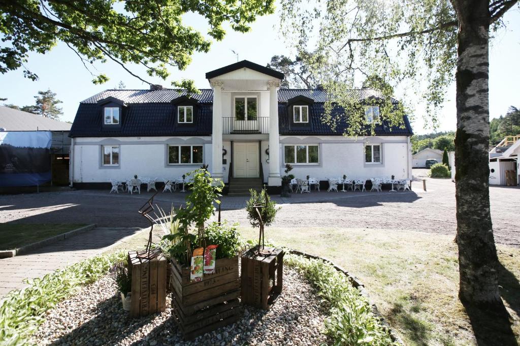 uma grande casa branca com um telhado preto em Hällsnäs Hotell & Restaurang em Mölnlycke