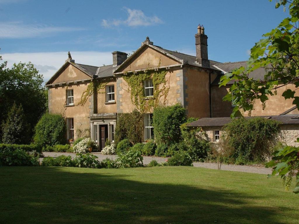 une ancienne maison en pierre avec une pelouse devant elle dans l'établissement Kilgraney House, à Bagenalstown