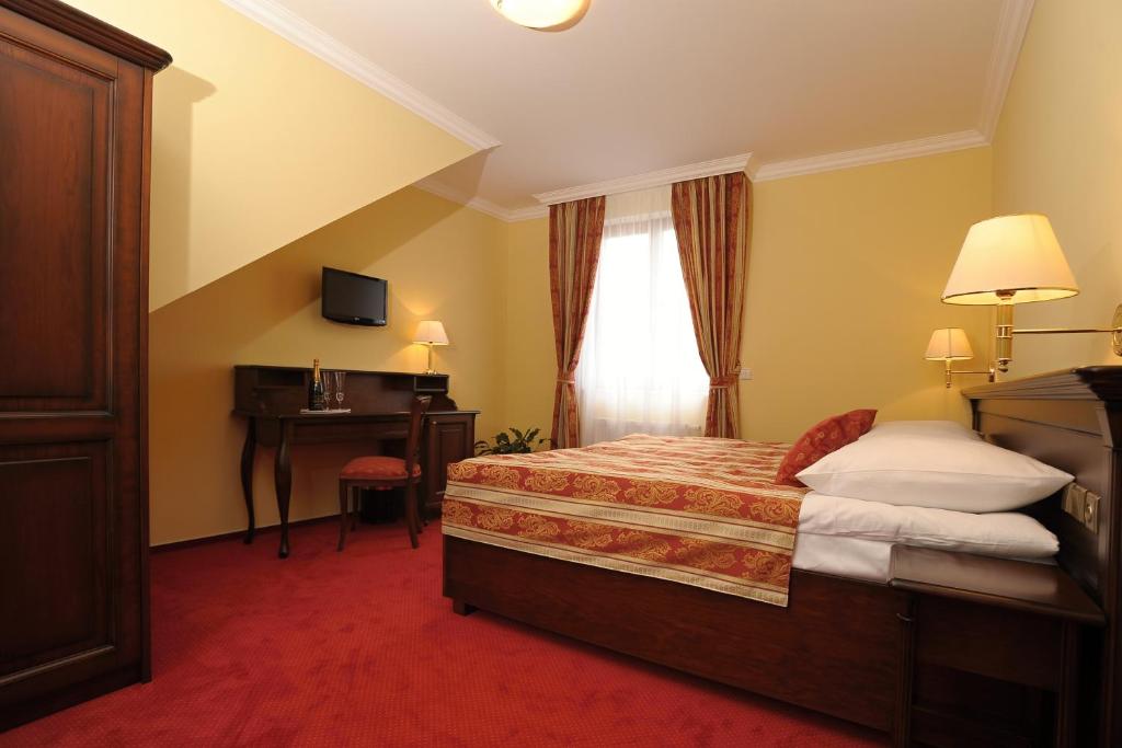 a hotel room with a bed and a desk at Hotel U Krále in Jičín