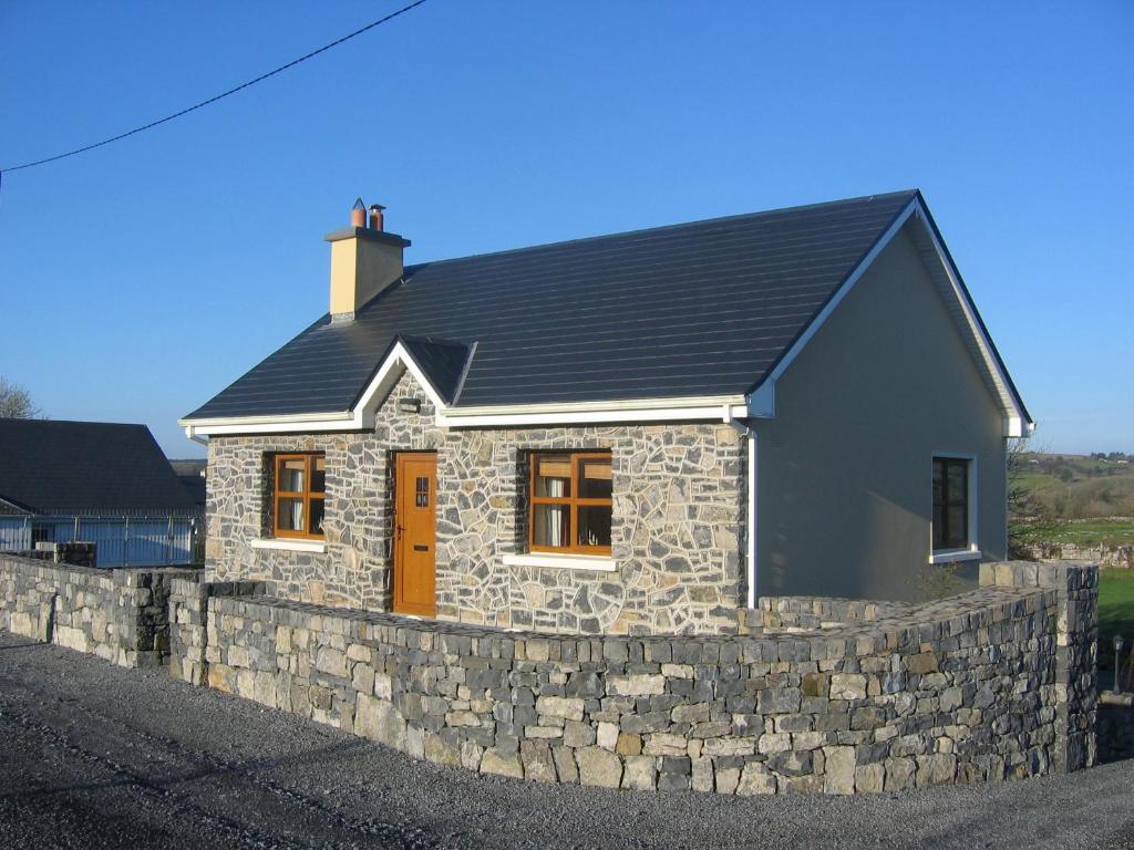 a stone house with a stone retaining wall at Roadside Cottage The Burren Kilfenora County Clare in Kilfenora