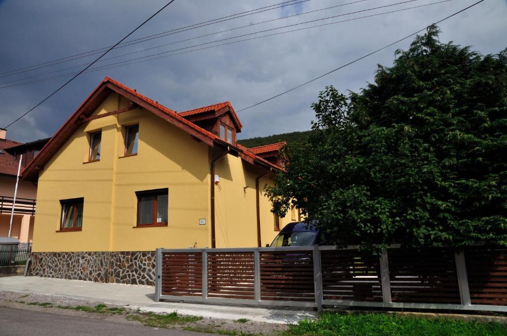 a yellow house with a fence in front of it at Ubytovanie Ahoj v prírode in Mýto pod Ďumbierom
