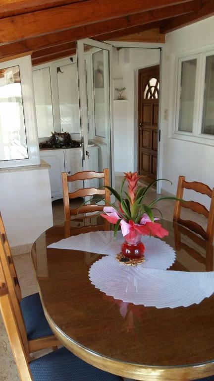 a dining room table with a vase of flowers on it at Apartmani Jašarević in Martinšćica