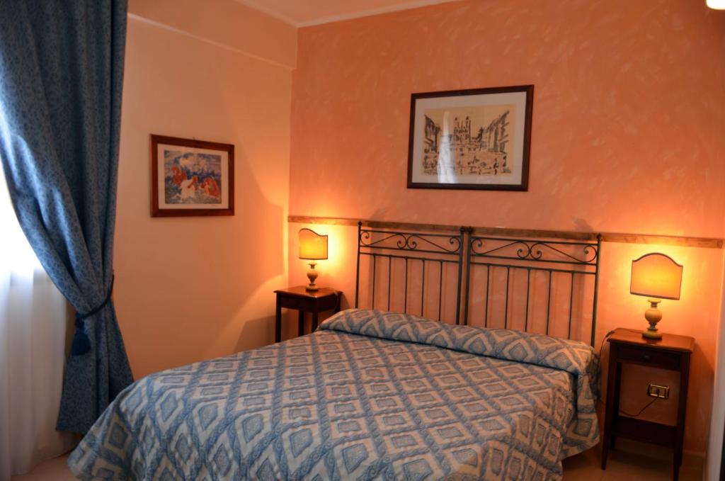 Priolo GargalloにあるHotel La Bussolaのベッドルーム1室(ベッド1台、ランプ2つ、窓付)