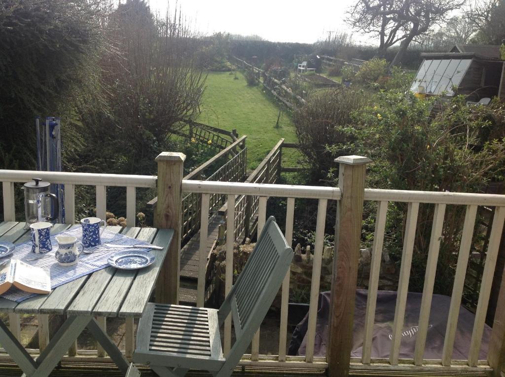 a wooden table and chairs on a wooden deck at Fern Dale Cottage in Stockland