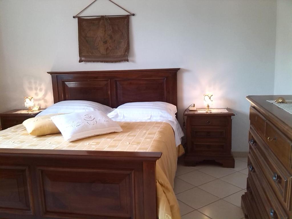 A Casa di Lavinia في كوارّاتا: غرفة نوم بسرير خشبي مع مواقف ليلتين