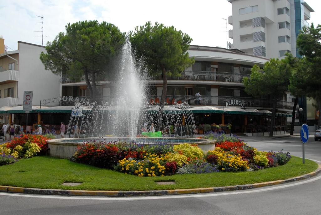 una fuente en medio de un parque con flores en Hotel Corallo, en Lignano Sabbiadoro