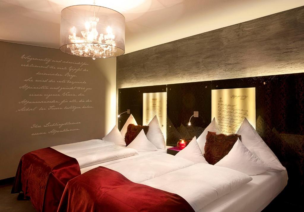 a room with three beds with white sheets and a chandelier at Hotel Sonne in Füssen