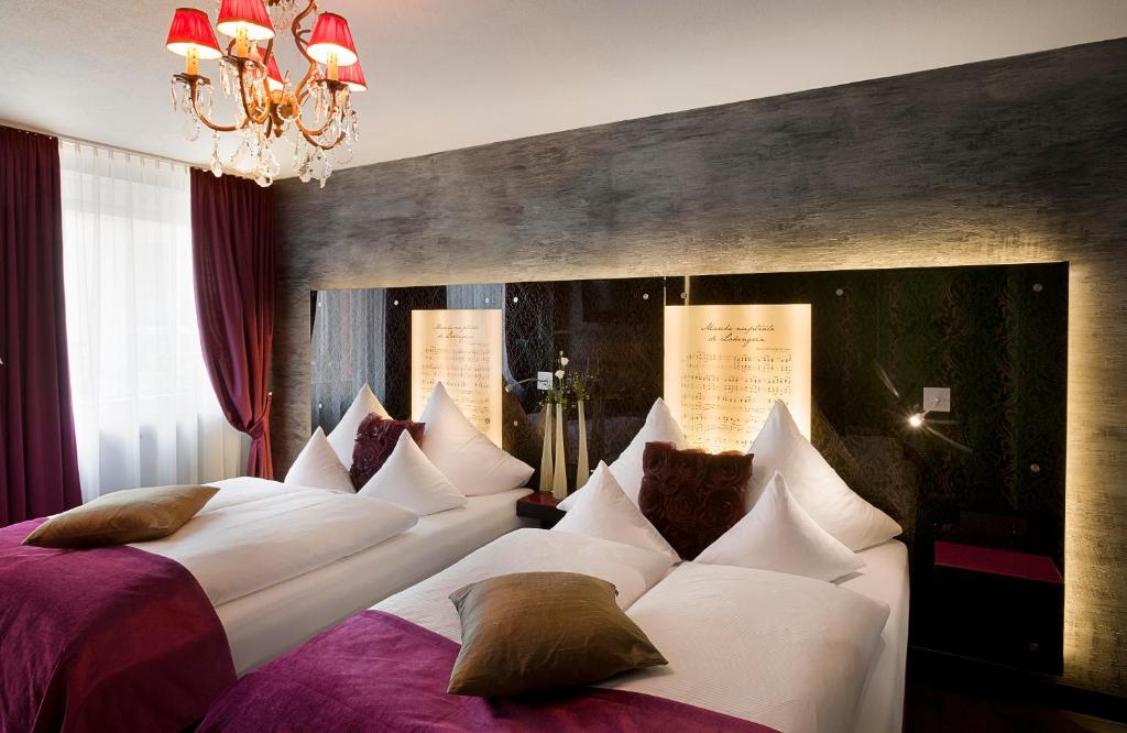 a bedroom with two beds and a chandelier at Hotel Sonne in Füssen