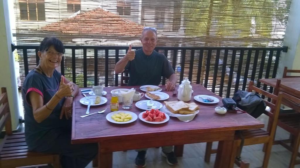un hombre y una mujer sentados en una mesa con comida en Hotel Pearl Gate en Chilaw