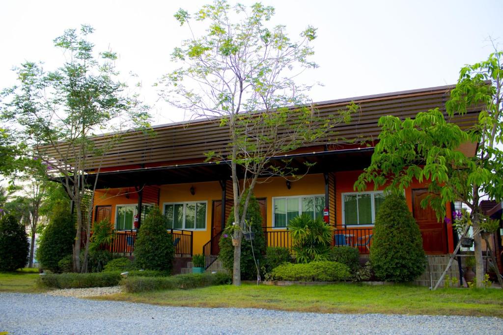 una casa roja y amarilla con árboles delante en Navy Sisatchanalai, en Ban Nong Chang