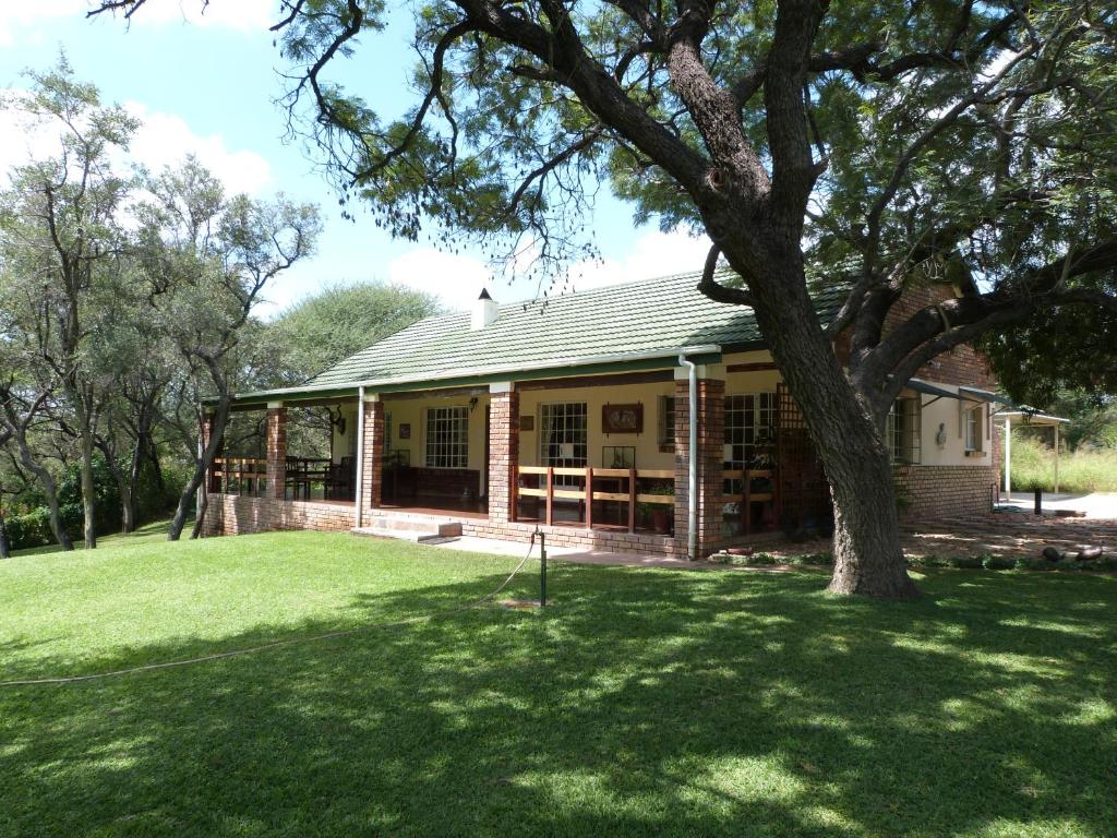 una casa con un albero nel cortile di Woodlands Stop Over and Lodge a Francistown