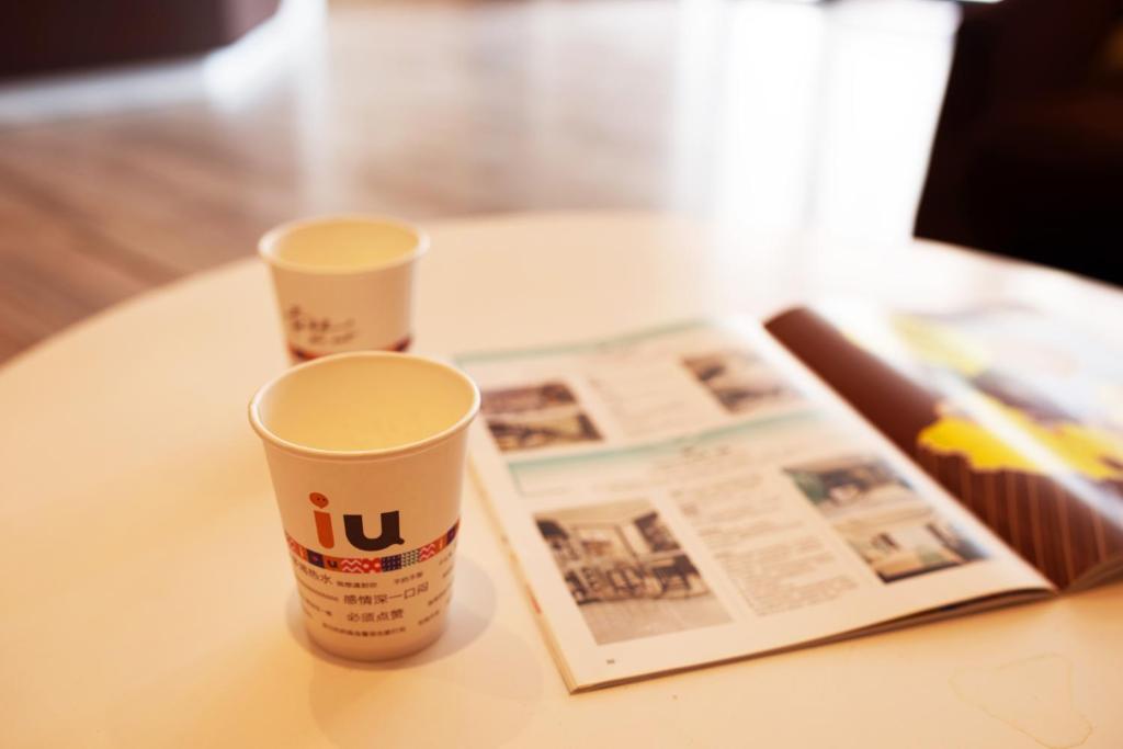 two cups sitting on a table next to a newspaper at IU Hotel Hezhou Bus Terminal in Hezhou